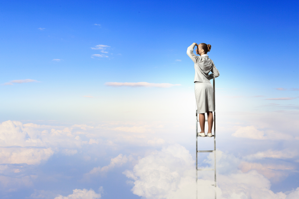 Businesswoman standing on ladder looking into distance against cloudy background