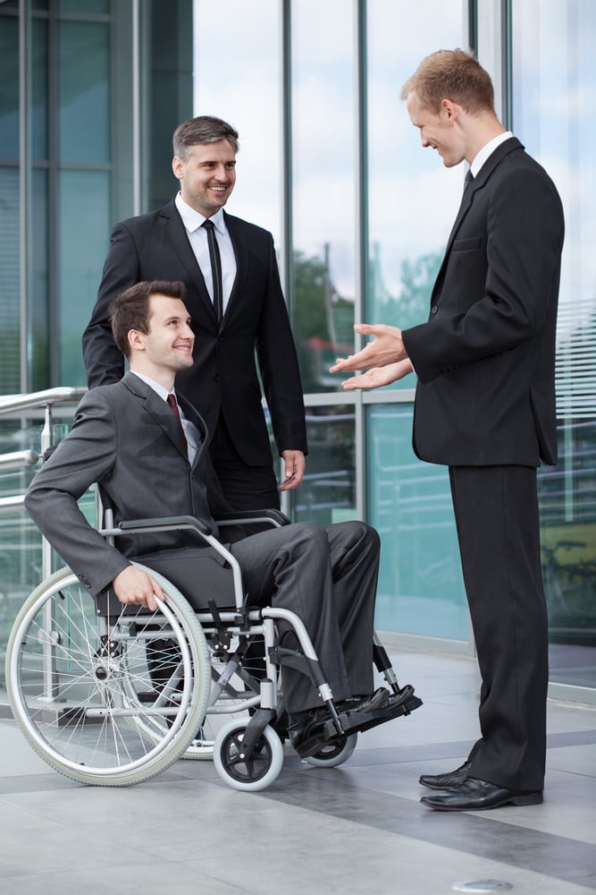 Young disabled businessman talking with his co-workers